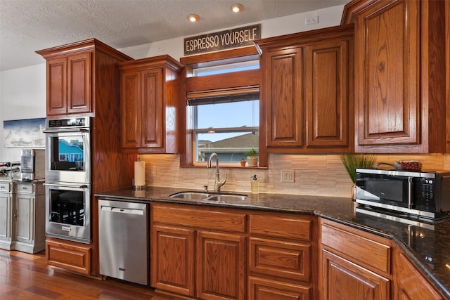 kitchen featuring dark stone countertops, appliances with stainless steel finishes, sink, and dark wood-type flooring