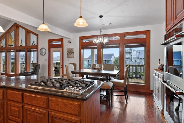 kitchen with decorative light fixtures, a chandelier, a textured ceiling, appliances with stainless steel finishes, and dark hardwood / wood-style flooring