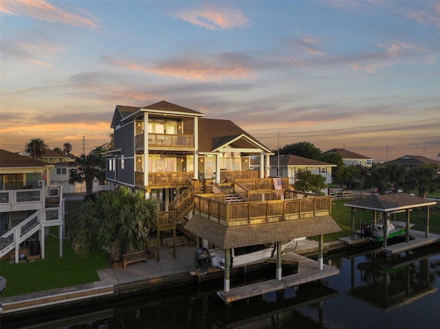 back house at dusk featuring a balcony and a water view