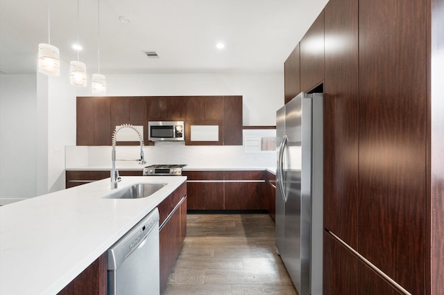 kitchen with hanging light fixtures, dark wood-type flooring, sink, and stainless steel appliances