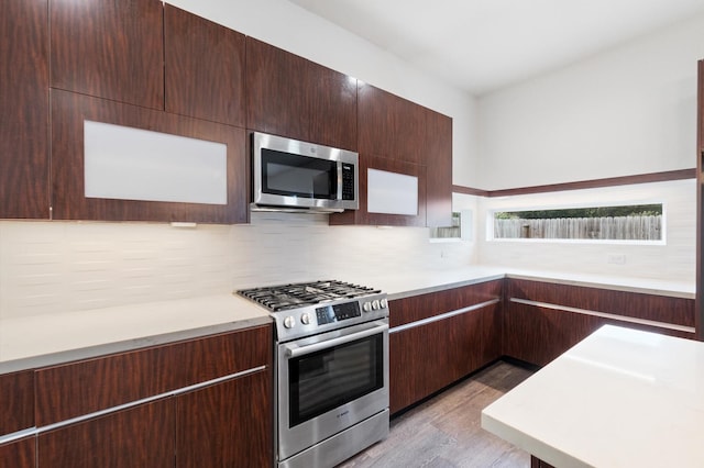 kitchen featuring appliances with stainless steel finishes, dark brown cabinetry, tasteful backsplash, and light hardwood / wood-style flooring