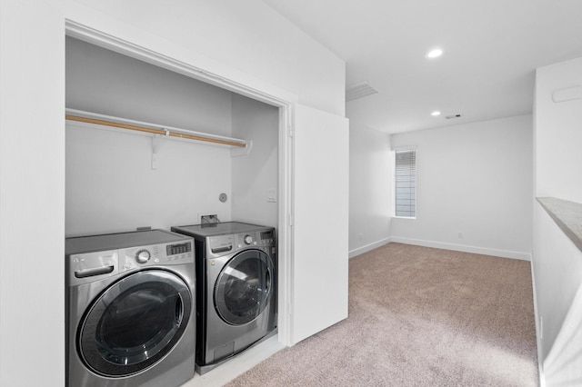 clothes washing area with separate washer and dryer and light carpet