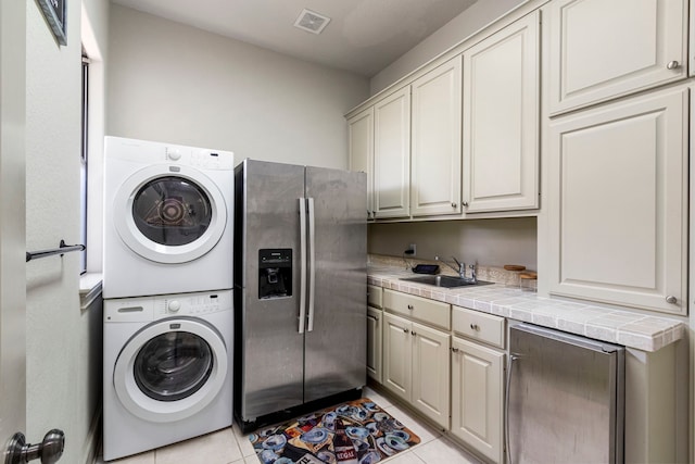 washroom featuring stacked washer and dryer, light tile patterned flooring, and sink