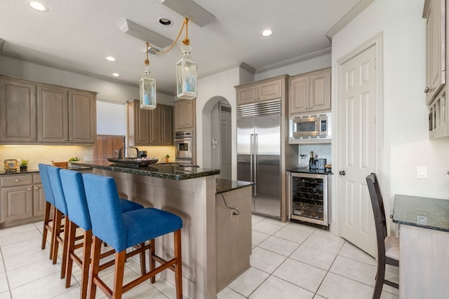 kitchen featuring light tile patterned flooring, ornamental molding, beverage cooler, backsplash, and built in appliances