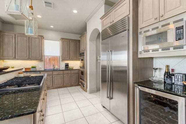 kitchen with pendant lighting, wine cooler, built in appliances, sink, and tasteful backsplash