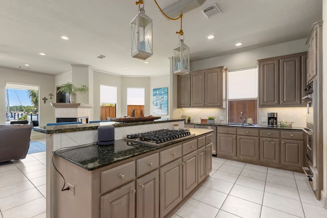 kitchen featuring appliances with stainless steel finishes, dark stone countertops, a kitchen island, and light tile patterned floors