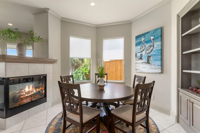 dining area with a tile fireplace, light tile patterned flooring, and crown molding