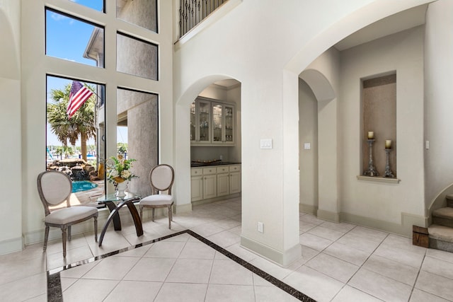 interior space with a towering ceiling, light tile patterned floors, and plenty of natural light