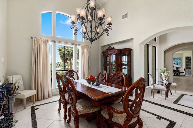 tiled dining space featuring a notable chandelier and a towering ceiling