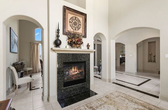 living area with light tile patterned flooring, a towering ceiling, and a premium fireplace