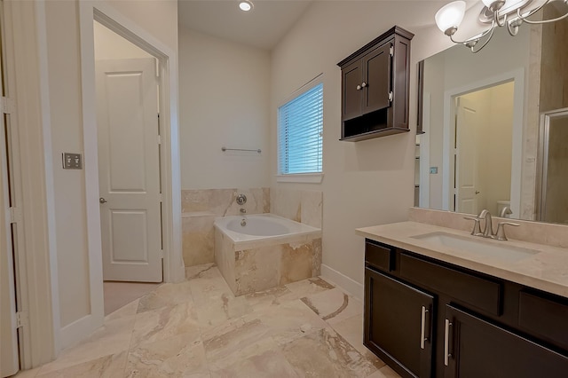 bathroom featuring tiled tub, vanity, and a notable chandelier