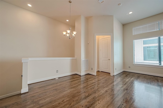 unfurnished room with hardwood / wood-style floors and an inviting chandelier