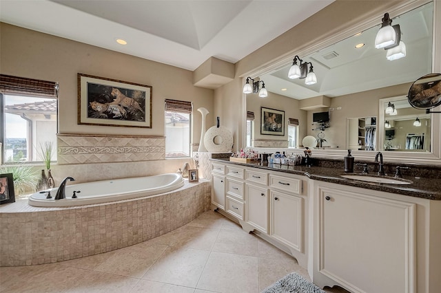 bathroom with tile patterned flooring, vanity, and tiled tub