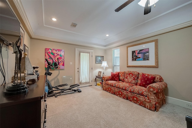 carpeted living room featuring a tray ceiling, ornamental molding, and ceiling fan