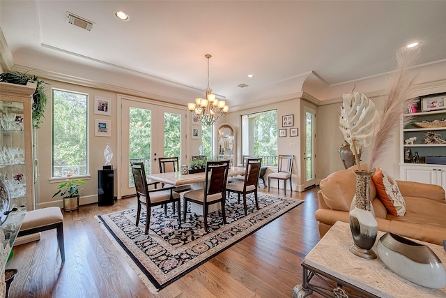 dining area featuring a notable chandelier, hardwood / wood-style flooring, ornamental molding, and french doors