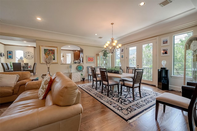 living room with crown molding, hardwood / wood-style floors, an inviting chandelier, and french doors