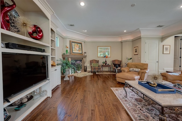 living room featuring wood-type flooring, built in features, and crown molding