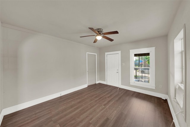 empty room featuring dark hardwood / wood-style flooring, a wall unit AC, and ceiling fan