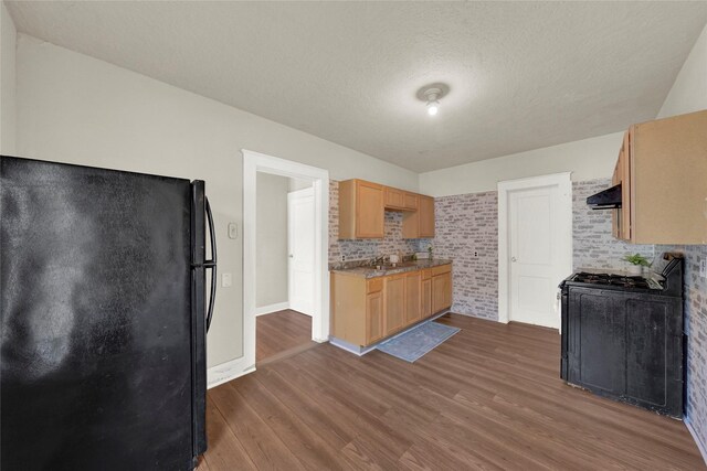 kitchen featuring light brown cabinets, black refrigerator, a textured ceiling, ventilation hood, and dark hardwood / wood-style flooring