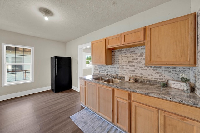 kitchen featuring light brown cabinetry, sink, black fridge, dark hardwood / wood-style floors, and a textured ceiling