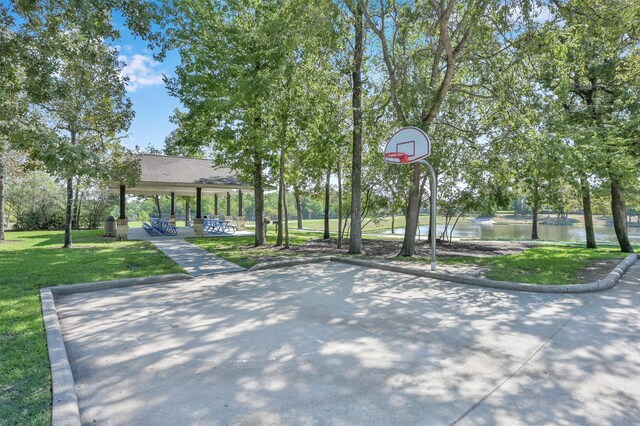 view of basketball court featuring a yard and a water view