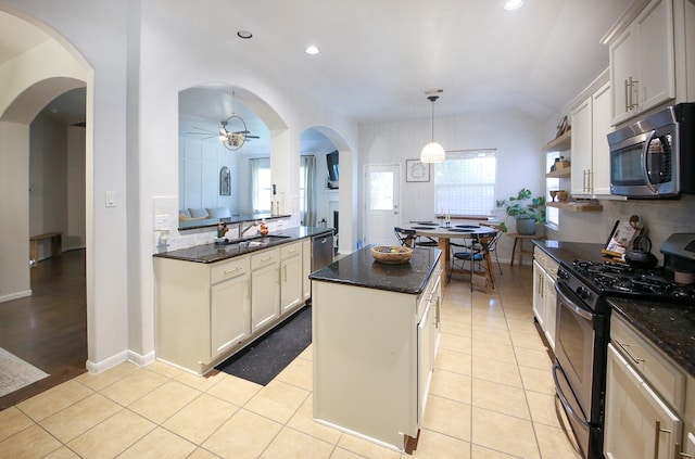 kitchen with lofted ceiling, a kitchen island, white cabinets, and stainless steel appliances