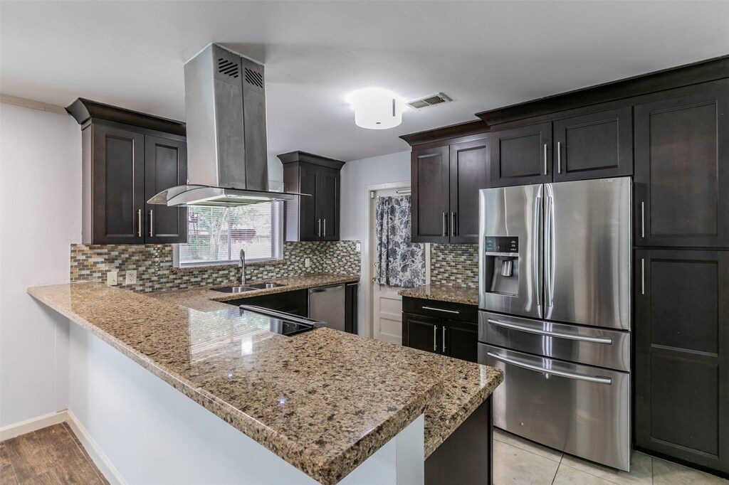 5215 Beechnut St, Houston, TX 77096 - kitchen with kitchen peninsula, light stone countertops, stainless steel appliances, sink, and exhaust hood