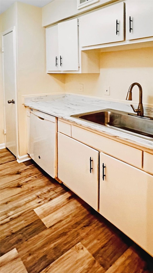 kitchen featuring white dishwasher, sink, light hardwood / wood-style flooring, and white cabinets