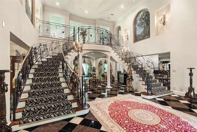 foyer with decorative columns, a high ceiling, and crown molding