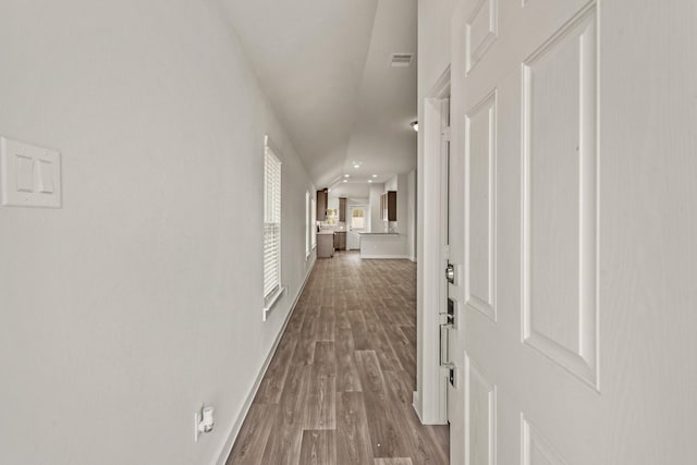 hallway featuring lofted ceiling and light wood-type flooring