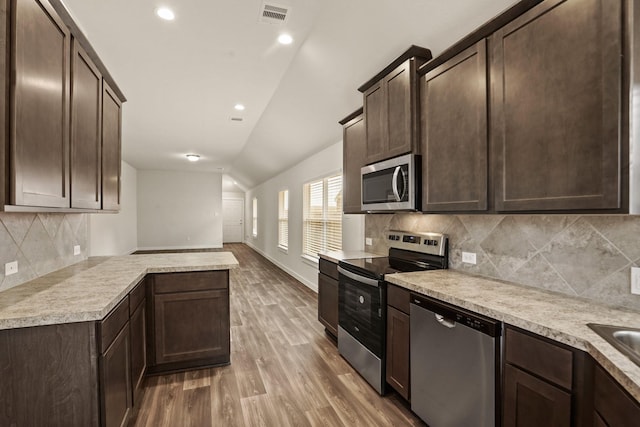 kitchen with hardwood / wood-style floors, decorative backsplash, dark brown cabinets, and appliances with stainless steel finishes