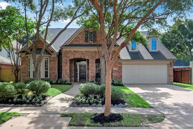 traditional home featuring fence, brick siding, and a shingled roof