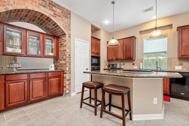 kitchen with visible vents, black appliances, a kitchen bar, and dark stone counters