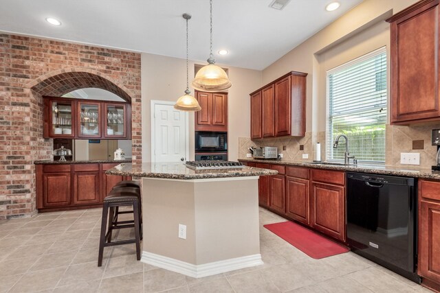 kitchen with a kitchen bar, black appliances, a sink, a center island, and dark stone counters