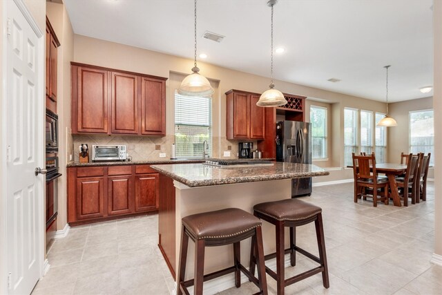 kitchen with visible vents, a kitchen island, a toaster, stainless steel appliances, and decorative backsplash