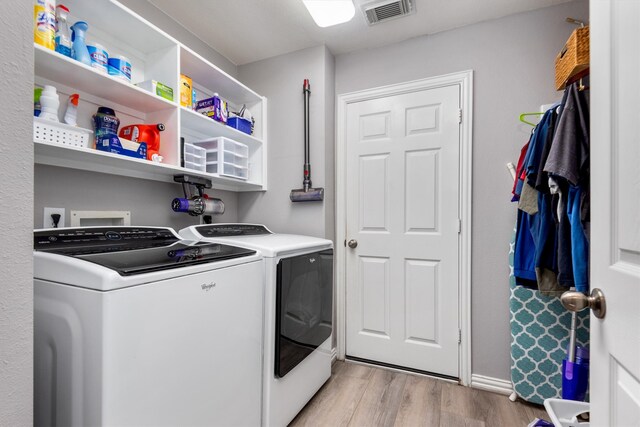 laundry room with visible vents, washing machine and dryer, laundry area, and light wood-style flooring