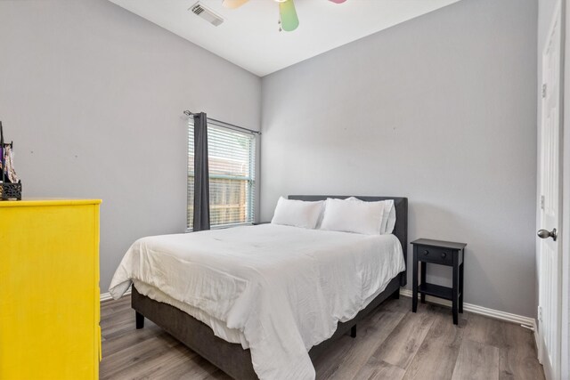 bedroom featuring ceiling fan, visible vents, baseboards, and wood finished floors