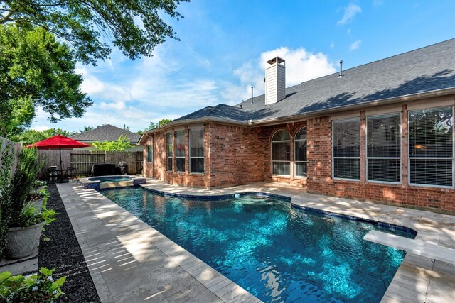 view of pool with a patio, a fenced backyard, a diving board, and a pool with connected hot tub