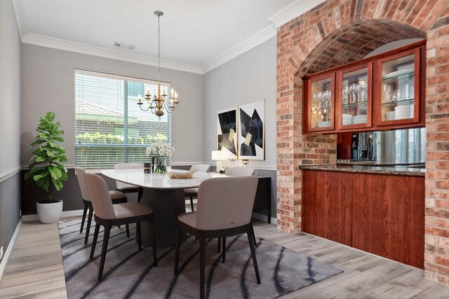 dining space with visible vents, an inviting chandelier, crown molding, light wood finished floors, and baseboards