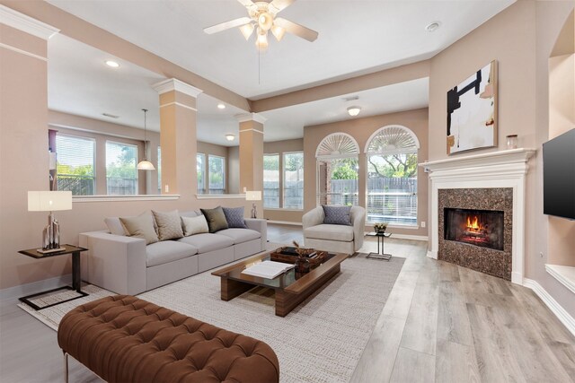 living room with light wood finished floors, baseboards, a wealth of natural light, and decorative columns