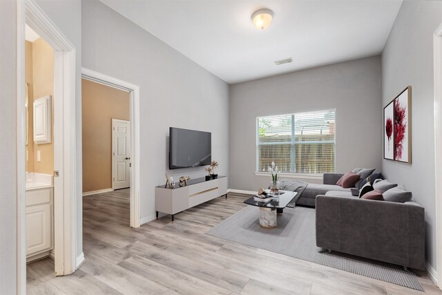 living area featuring visible vents, light wood-type flooring, and baseboards