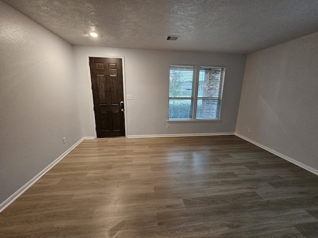 foyer entrance with a textured ceiling and dark wood-type flooring