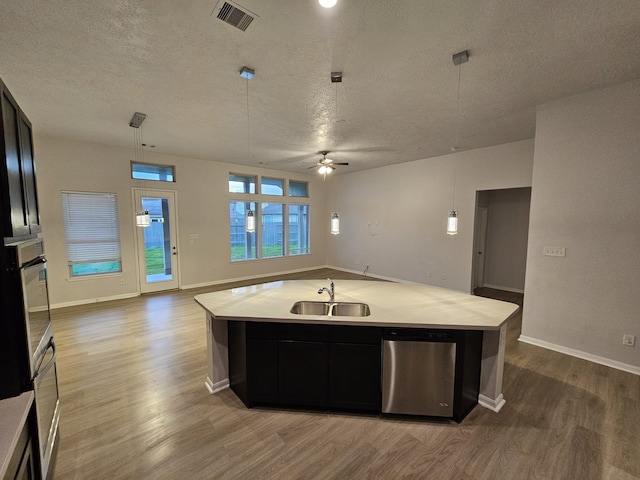 kitchen featuring decorative light fixtures, an island with sink, ceiling fan, and sink