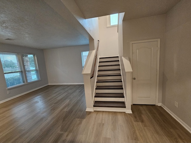 stairs with hardwood / wood-style floors and a textured ceiling