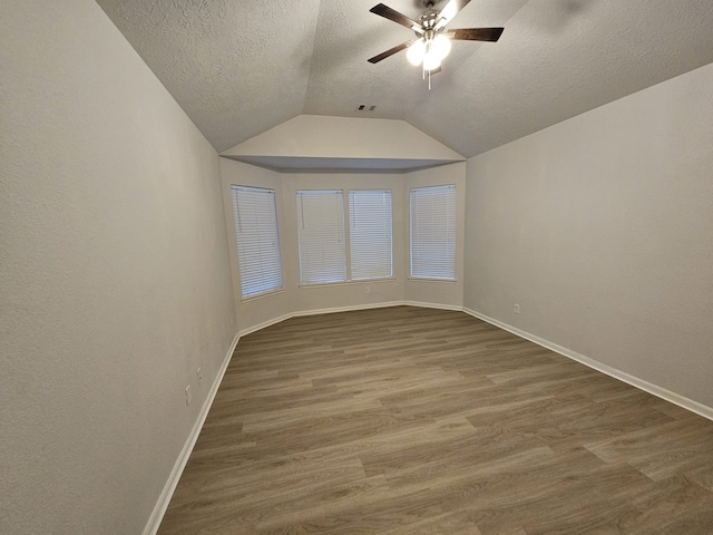 spare room with a textured ceiling, dark hardwood / wood-style floors, ceiling fan, and lofted ceiling