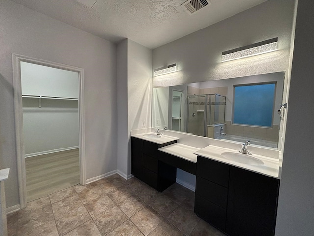 bathroom with vanity, a textured ceiling, and separate shower and tub