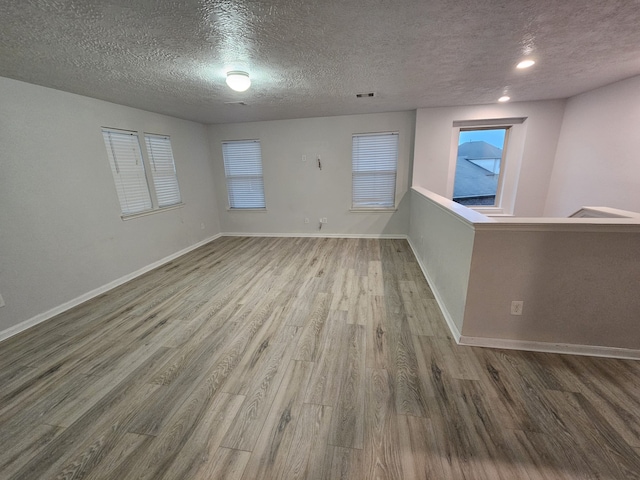 unfurnished room featuring wood-type flooring and a textured ceiling