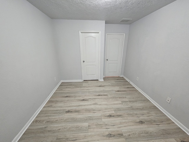 interior space with a textured ceiling and light hardwood / wood-style flooring