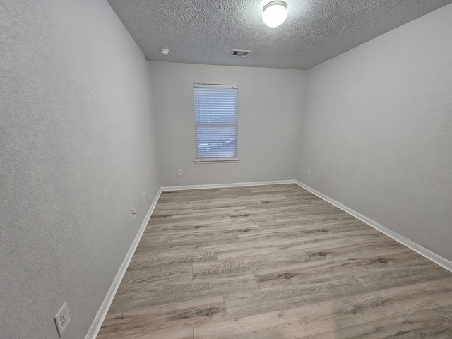 spare room featuring a textured ceiling and light hardwood / wood-style flooring