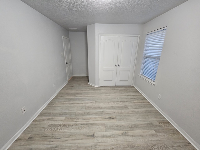 unfurnished bedroom with a closet, light hardwood / wood-style floors, and a textured ceiling